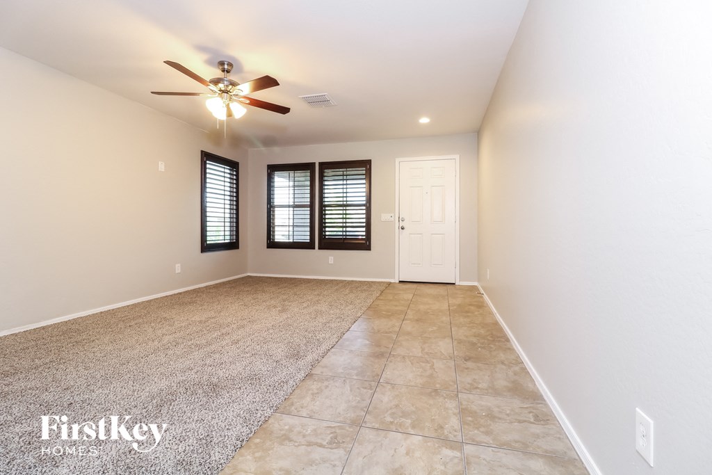 the spacious living room with tile flooring and a ceiling fan