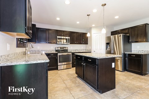 a large kitchen with black cabinets and stainless steel appliances