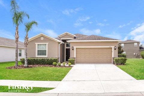 a beige house with a garage and palm trees