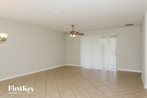 an empty living room with white walls and a ceiling fan