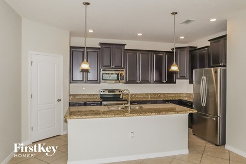 a kitchen with granite counter tops and black cabinets and stainless steel appliances