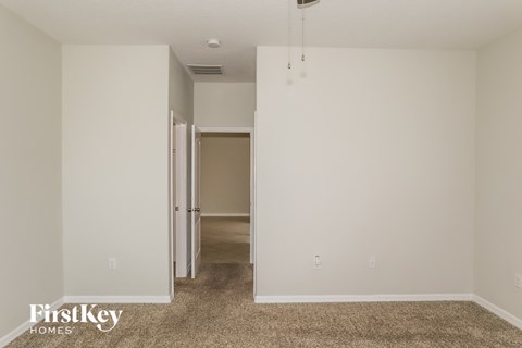 a bedroom with white walls and carpet and a door to a hallway