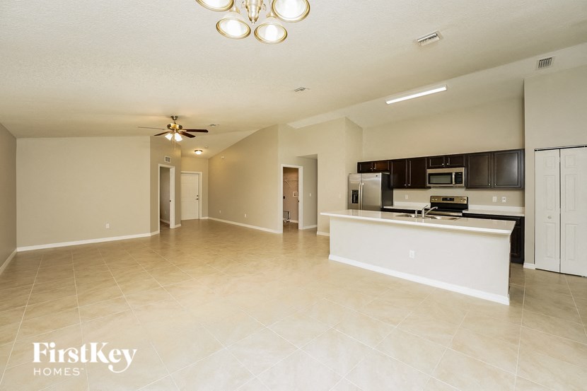 A spacious living room with a kitchen area in the background.