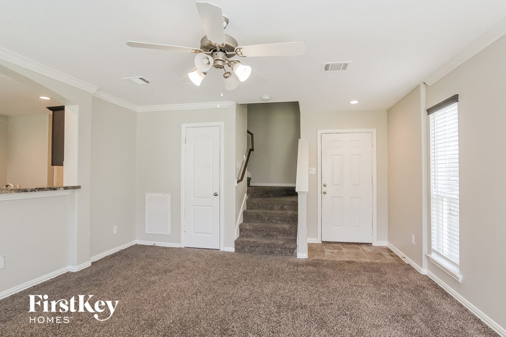 A spacious room with a carpeted floor and a staircase leading to another room.