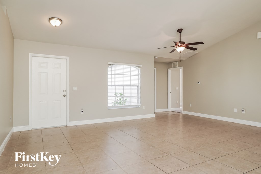 A spacious room with a ceiling fan and tile flooring.