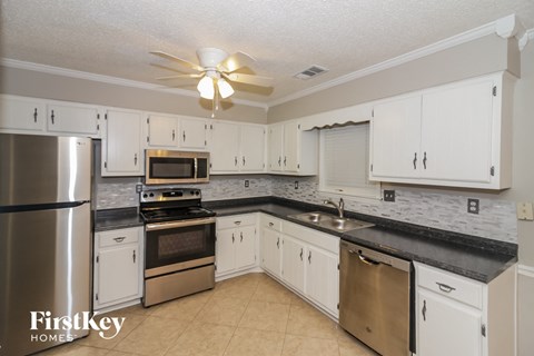A kitchen with white cabinets and a black counter top.