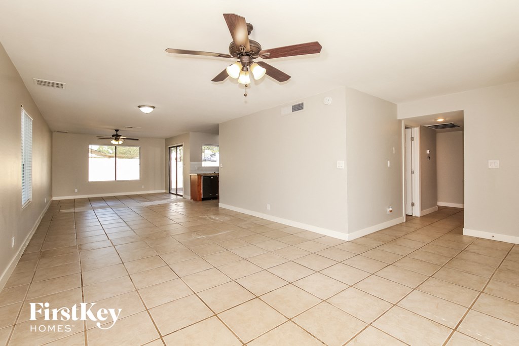 an empty living room with a ceiling fan and tiled floors