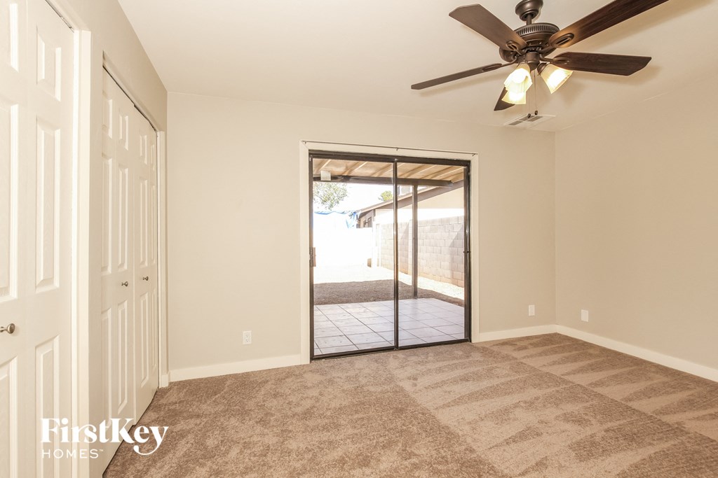 an empty living room with a ceiling fan and a door to a patio