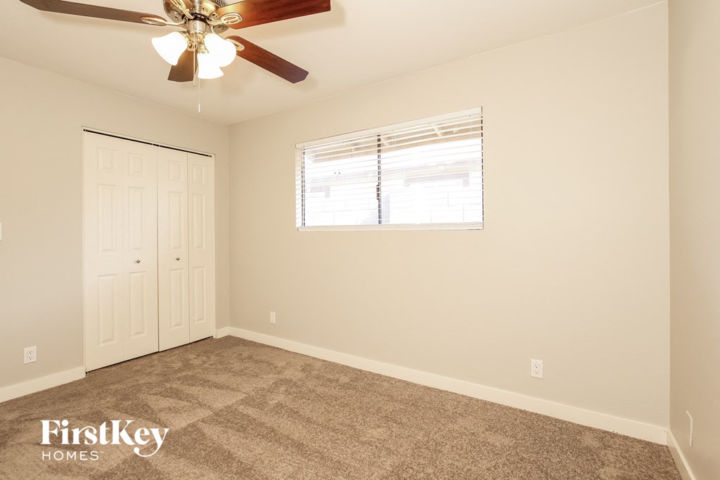 the living room of an empty home with a ceiling fan and a window