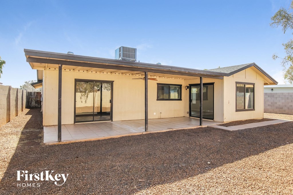 a small yellow house with glass doors and a gravel yard