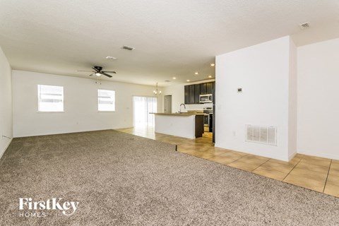 A spacious empty room with a fan on the ceiling and a carpet on the floor.
