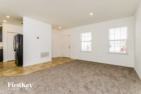 A spacious room with a carpeted floor and two windows.