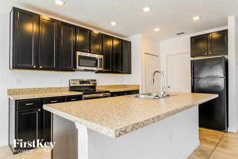 A kitchen with black cabinets and a granite countertop.