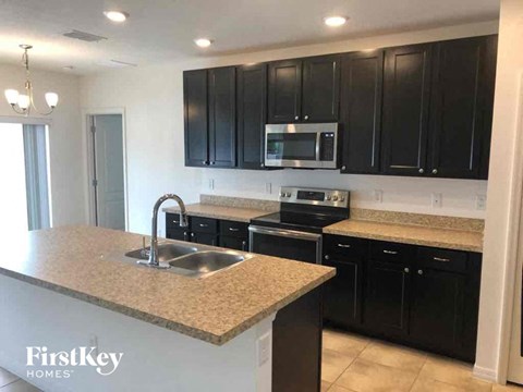 A kitchen with black cabinets and a granite countertop.
