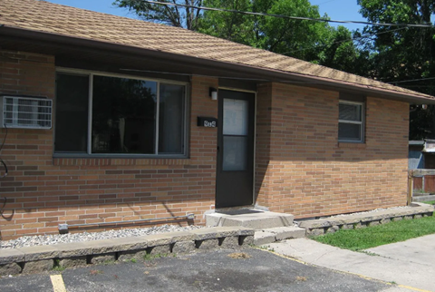 A brick house with a black door and windows.