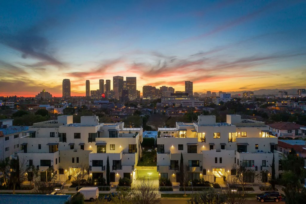 A cityscape at dusk with buildings illuminated and a clear sky.