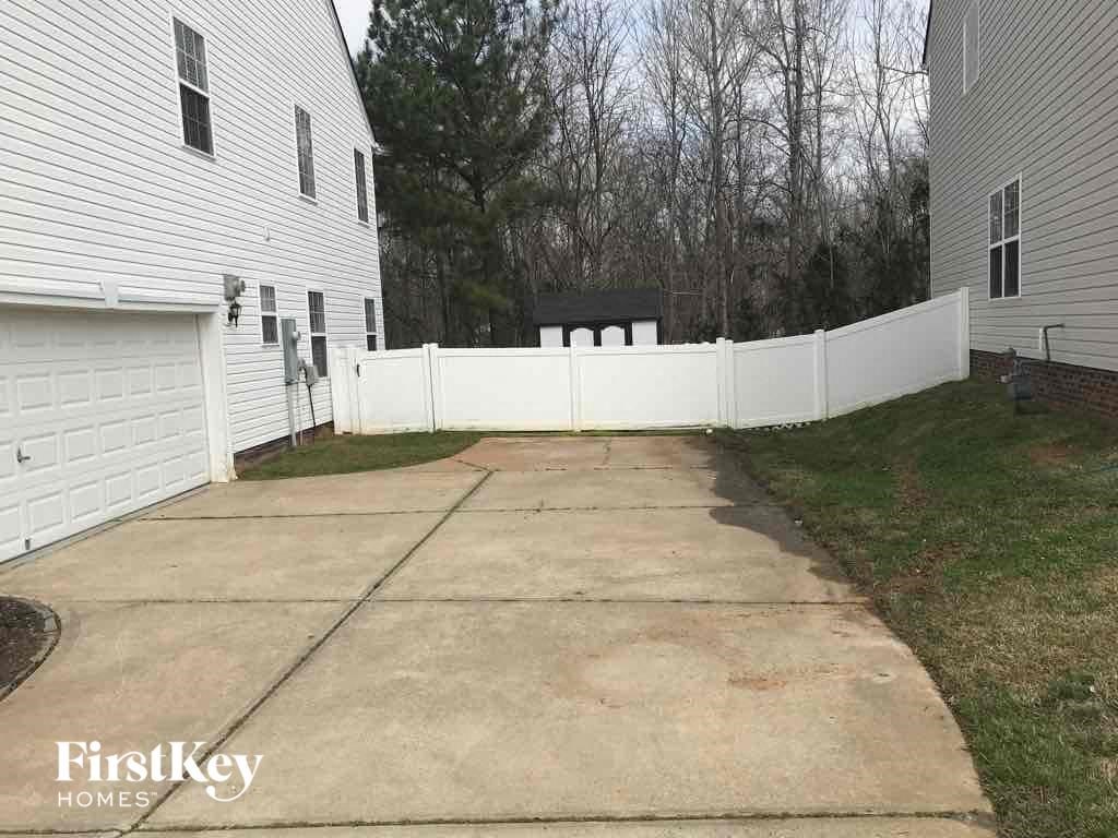 a white fence surrounds a driveway in front of a house