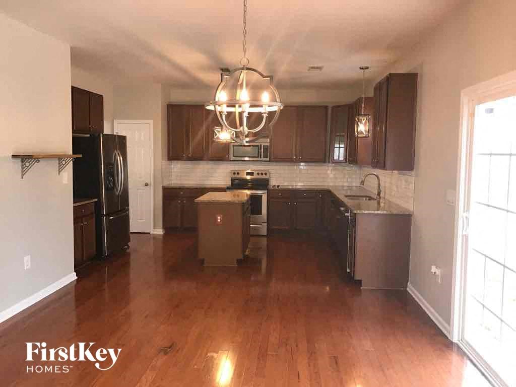 an empty kitchen with wooden floors and stainless steel appliances