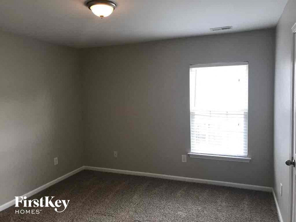 a bedroom with a window and a carpeted floor