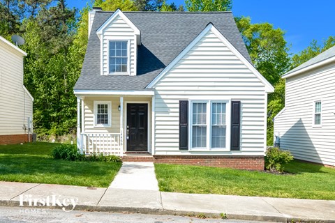 a white house with black shutters and a lawn