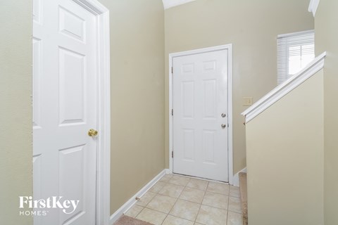 a small hallway with two white doors and a staircase