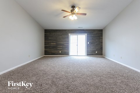 the living room of an empty house with a ceiling fan