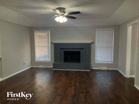 an empty living room with a fireplace and a ceiling fan