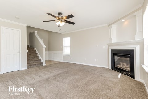 A spacious living room with a fireplace and a ceiling fan.
