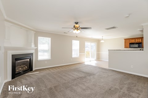 A spacious living room with a fireplace and a ceiling fan.