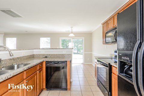 A kitchen with a black fridge and wooden cabinets.