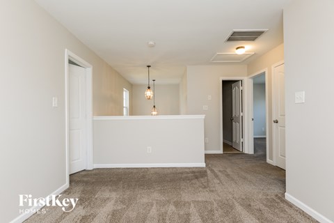 A spacious room with a carpeted floor and a white wall.
