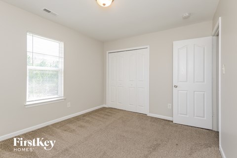 A room with a carpeted floor, two doors, and a window.