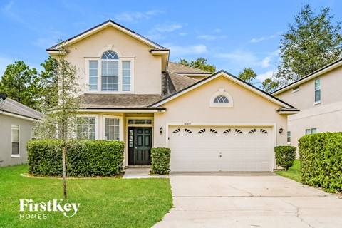 a beige house with a garage door and a lawn