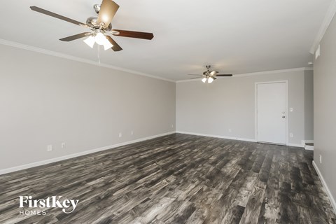 the living room of a home with wood flooring and ceiling fans