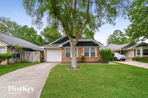 a brick house with a white garage door and a tree in the yard