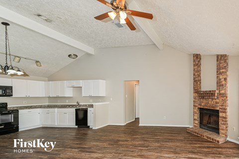a kitchen and living room with a fireplace and a ceiling fan