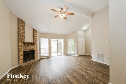 an empty living room with a fireplace and a ceiling fan