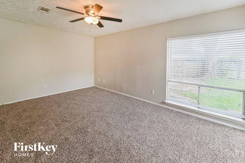 a bedroom with a large window and a ceiling fan