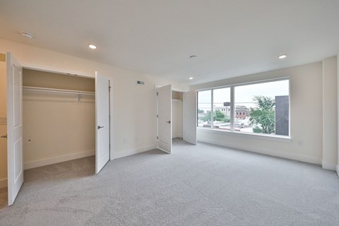 an empty living room with a large window and a closet