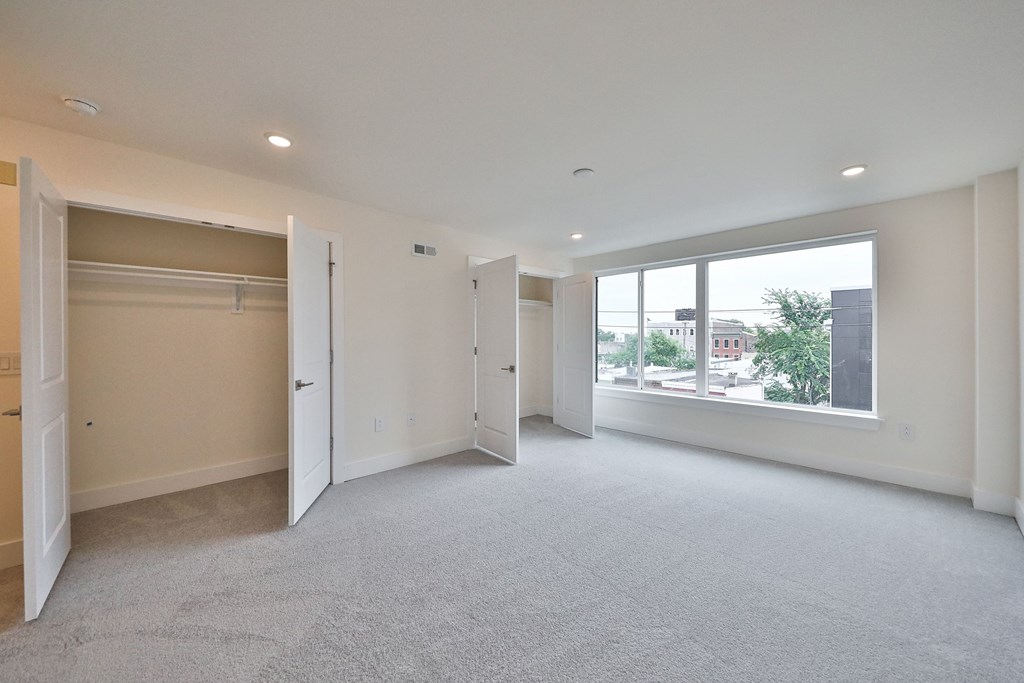 an empty living room with a large window and a closet