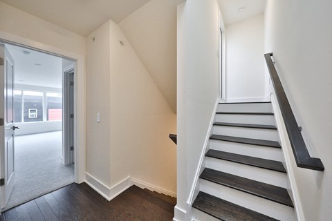 an empty hallway with a staircase and a door to a living room