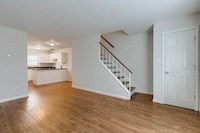 an empty living room with a staircase and a kitchen