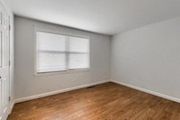 an empty bedroom with a window and wooden floors
