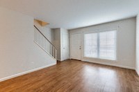 an empty living room with a large window and wooden floors