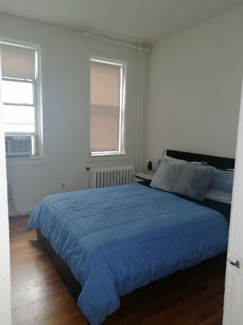 a bedroom with a blue bed and two windows