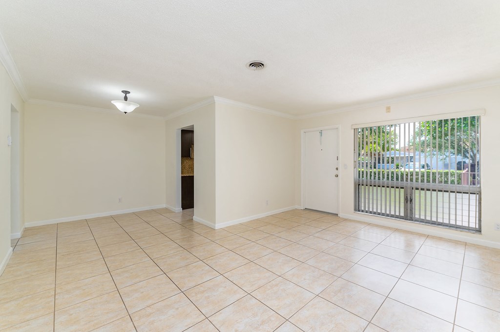 an empty living room with a large window and tiled floors