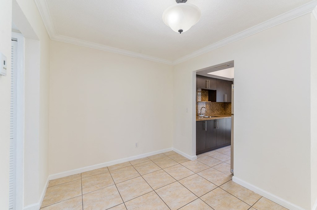 an empty living room with a tile floor and a kitchen