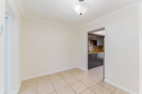 an empty living room with a tile floor and a kitchen