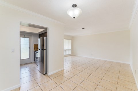 an empty living room with a refrigerator in the middle of it