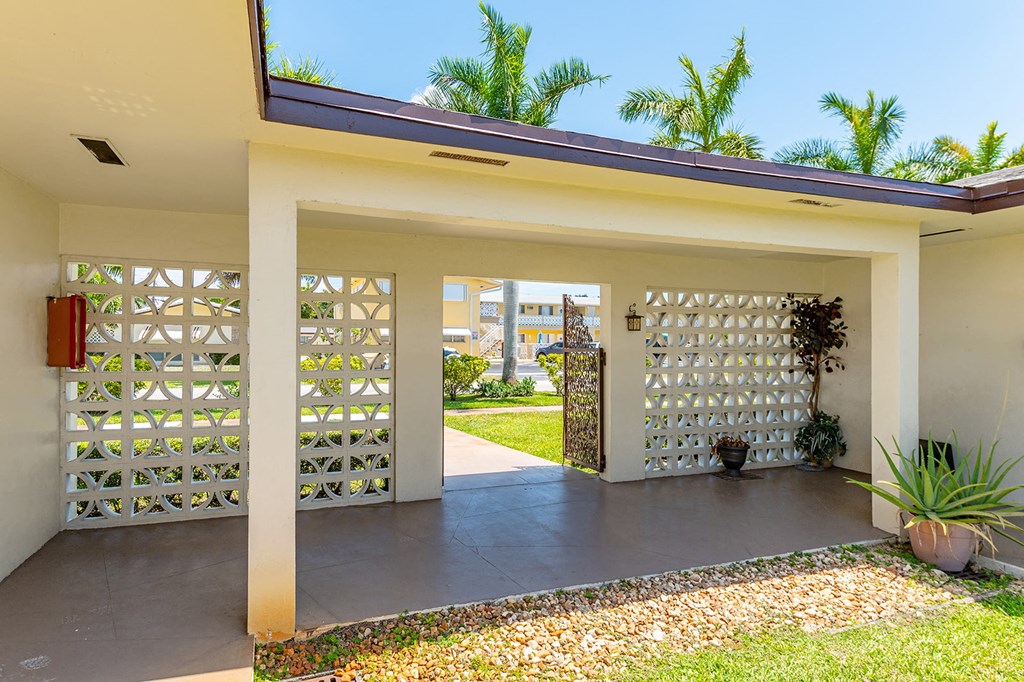 a view of the entrance to a house with a yard and palm trees